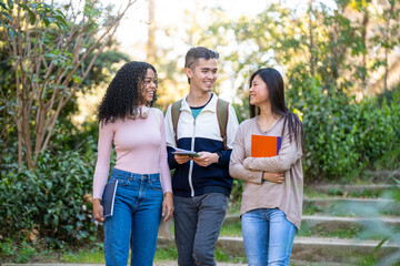 Three young multiethnic students walking in the street and talking