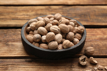 Plate with nutmeg seeds on wooden table