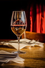 Glass of red wine sitting on a sunlit table in a urban cafe.