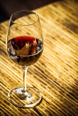 Glass of red wine sitting on a sunlit table in a urban cafe.