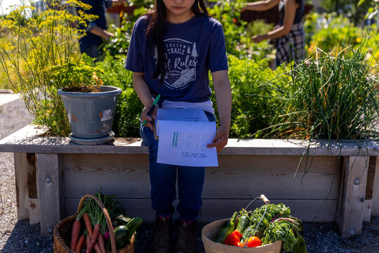 Young woman with Down syndrome planning in sunny, urban community garden