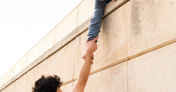 Crop person holding hand of man on building