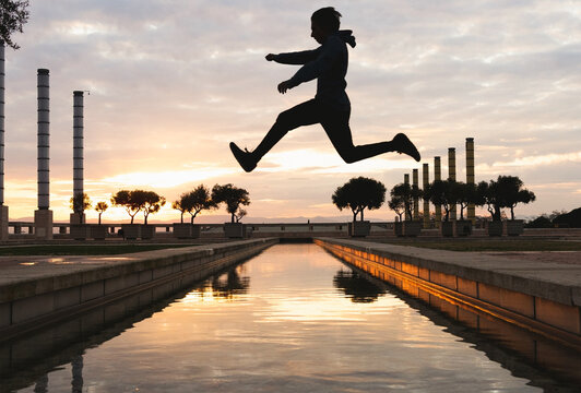 Jumping silhouette of active person over sunset