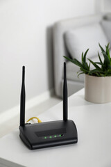Modern Wi-Fi router on white table in room