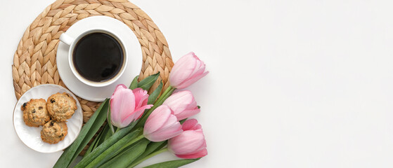 White cup of coffee with pink tulips on white background. Morning coffee on wicker tray. View from above of morning coffee, cookies and flowers. Flat lay. Breakfast in bed. Stylish home interior decor