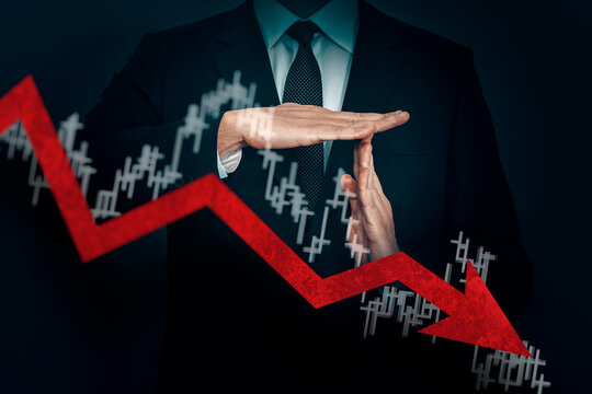 A businessman in a suit holds hands in a timeout on dark background.  Glowing red arrow going downwards. Recession, inflation, economic crisis.
