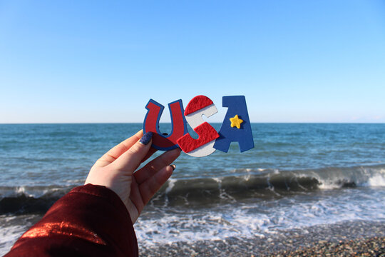 USA lettering inscription in front of blue sky and sea. Idea for USA study, travel, election