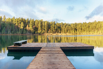 Obraz premium Pier with a bench on a beautiful lake in autumn