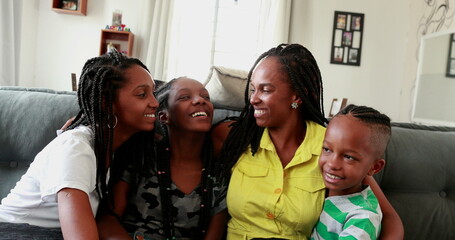 African mother and children sitting at home couch smiling, real people