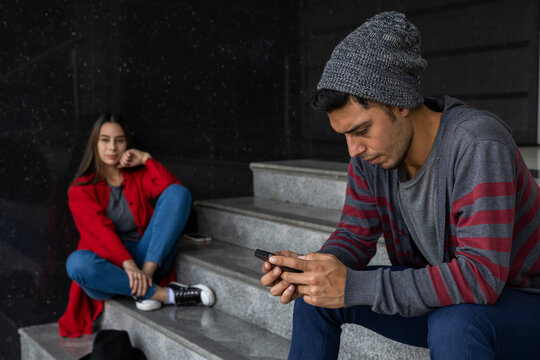 Two young Latin American brothers hanging out sitting on the stairs. Selective approach. Technology and brotherhood concept
