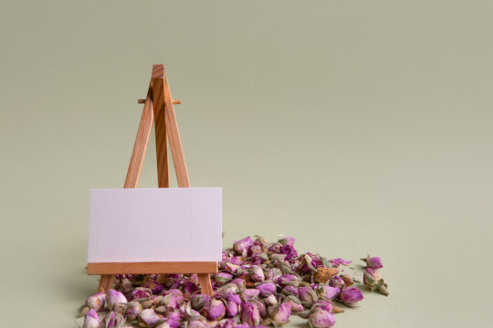blank business card template lies on an easel with dried rose flowers close-up. place for your design. layout for a future business card. - Powered by Adobe