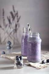 a smoothie made of fresh milk with oatmeal and blueberries is on the table in a glass jar	