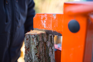 Close-up shot of a hydraulic wood splitter cutting fire wood on a sunny day