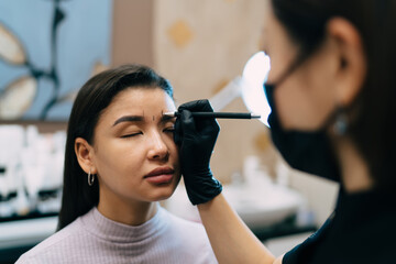 Beautician do eyebrow microblading of asian girl