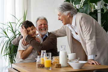Happy mixed race family. Smiling grandparents having fun with boy grandchild together at home.