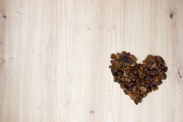 Raisin heart on wooden background. Rich in fibers, provides energy, is rich in antioxidants, vitamins and minerals