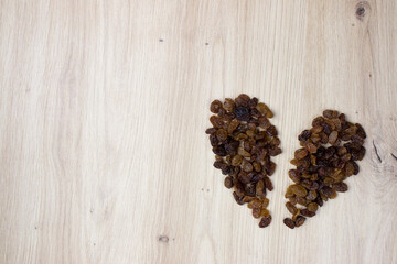 Broken heart of raisins on wooden background. Rich in fibers, provides energy, is rich in antioxidants, vitamins and minerals