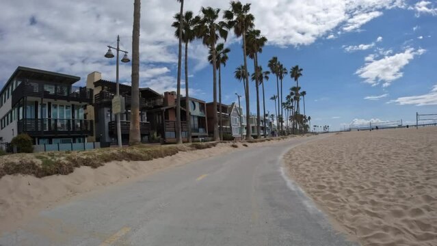 Slow moving view of homes and palm trees on the Venice beach bike path in Southern California.