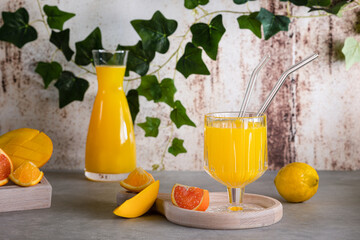 Glass of fresh orange juice with fresh fruit on a wooden table Still life with fresh orange juice in a glass with splashes and drops. The juice is pouring from the decanter into the glass