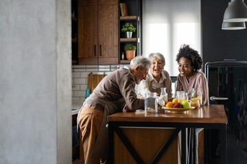Black woman together with caucasian grandparents in kitchen