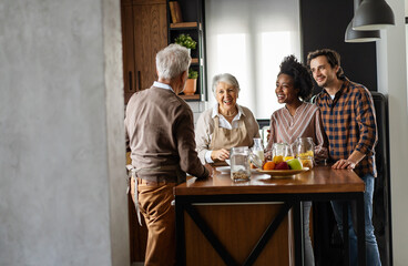 Multi generation multiethnic family having fun, talking around a festive kitchen table.