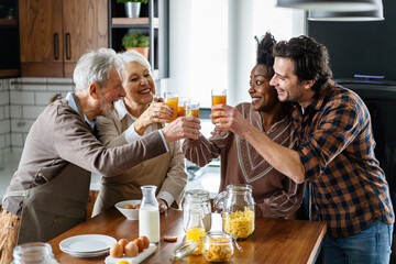 Multi generation multiethnic family having fun, talking around a festive kitchen table.