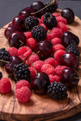 strawberries, blackberries and cherries on wooden chopping board