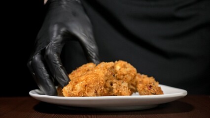 Cool beautiful fresh juicy cooked chicken wings in breading. Buffalo wings spread on food white plate in table. Very tasty and beautiful. Cooking with deep fryer fry machine.