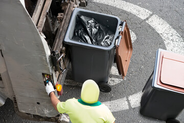 waste worker  of municipality  service unfocused carrying the containers bins to the garbage truck...