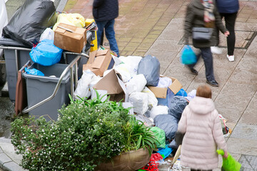 people walking near many bags with rubbish out of  bins on city street , garbage workers strike...