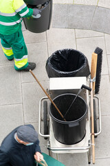 sweeper worker of  public service company with equipment collect the waste bags on bins of  city...