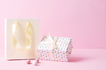 A yellow paper bag and a gift on a pink background. Easter shopping for the holiday, a selective focus