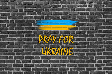 Fototapeta premium Pray for Ukraine (Support Ukrainians). Brick Wall