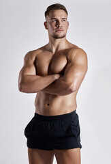 He takes fitness serious and it shows. Shot of a muscular young man posing against a white background.