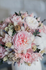 Bouquet with roses, hydrangea. Stabilized flowers in a white ceramic vase at home. Flowers decor for home.