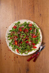 Salad with parma ham on wooden table.