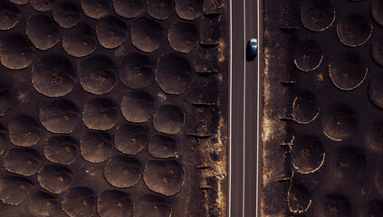 Lunar landscape concept with long asphalt road and car traveling. Rare holes on the ground like...