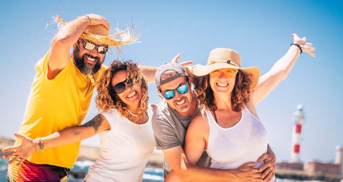 Group of cheerful tourist have fun and pose for a picture in summer holiday vacation together. Concept of friendship and outdoor funny leisure activity. Two couples men and women enjoy sun