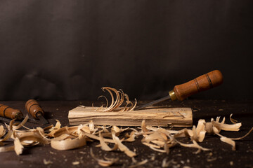 Chisel with wood shavings. Carpenter cabinet maker hand tools on the workbench. - obrazy, fototapety, plakaty
