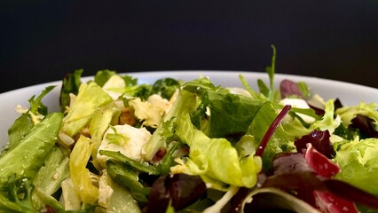 Fresh greek salad - feta cheese, lettuce, black olives and chicken on black background