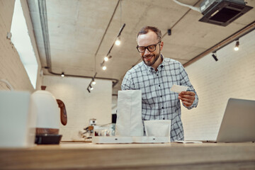 Cheerful cafe owner preparing order for customer