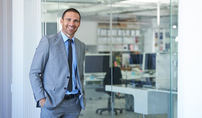 Hes a corporate heavyweight. Shot of a handsome businessman standing in his office.
