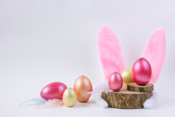 Easter Wooden colored eggs on saw cut of a tree with feathers and bunny ears.