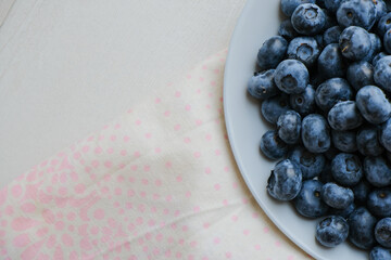 Fresh raw organic blueberries in a plate on a natural linen napkin on the table. Healthy nutrition. Minimalistic simple natural light flat lay template. Superfood. Organic eco health care. Vitamins.