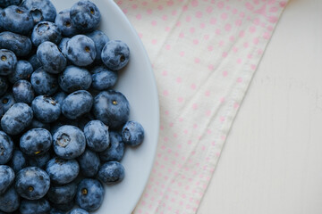 Fresh raw organic blueberries in a plate on a natural linen napkin on the table. Healthy nutrition. Minimalistic simple natural light flat lay template. Superfood. Organic eco health care. Vitamins.