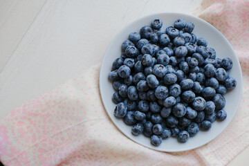 Fresh raw organic blueberries in a plate on a natural linen napkin on the table. Healthy nutrition. Minimalistic simple natural light flat lay template. Superfood. Organic eco health care. Vitamins.