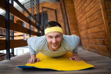 Young athletic man is training at home, doing exercise, working hard to maintain body shape in isolation.