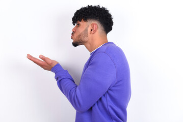 Profile side view view portrait of attractive young arab man with curly hair wearing purple...