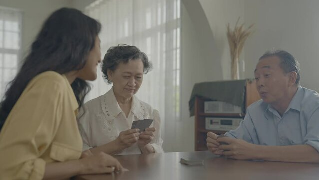 Holiday concept of 4k Resolution. Asian families take turns discarding cards on the table while playing games at home. Family gambling games.