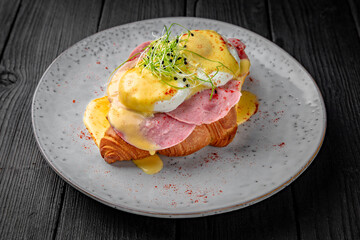 Croissant sandwich with tender ham, poached eggs and cheese. Healthy, tasty, nourishing snack. Take away food